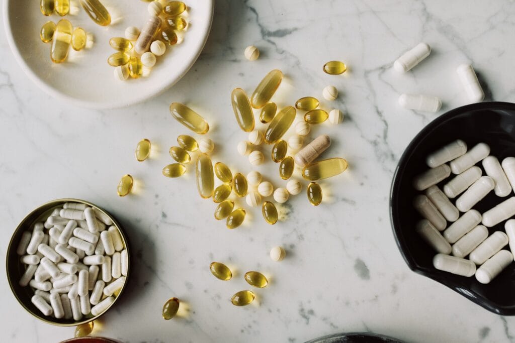Assorted dietary supplement capsules and softgels on a marble surface.